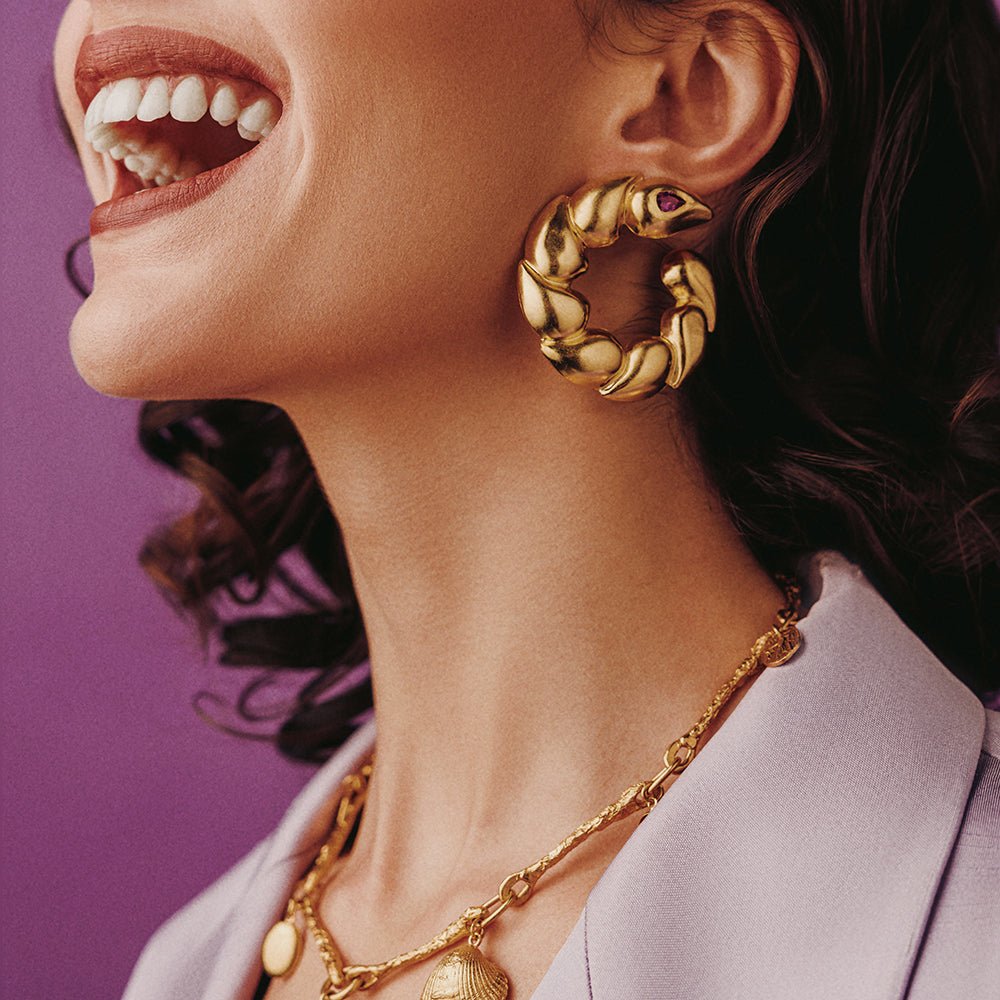 Beautiful Chunky Gold Hoop earrings worn by a woman laughing against a purple backdrop